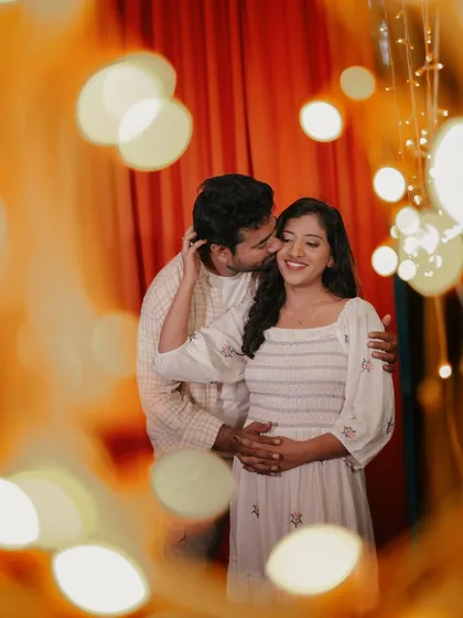 A tender moment between a couple, with the warm, out-of-focus lights creating a dreamy and artistic frame.