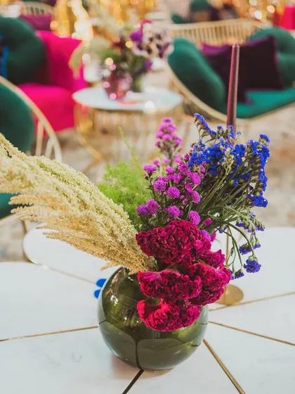 A beautiful mix of dried and fresh flowers in jewel tones, creating a rich and textured arrangement for a side table.