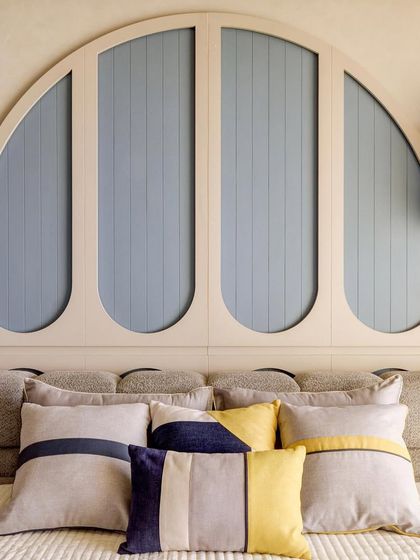 A close-up of the custom arched headboard in a child's room. The playful design and soft blue color create a comforting and stylish focal point in the space.