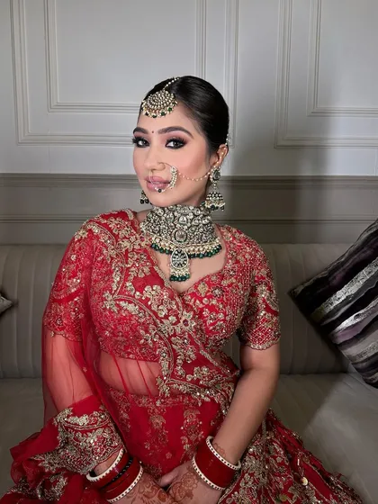 This bride looks ethereal and glowing in her red lehenga, paired with a heavy polki and emerald choker.
