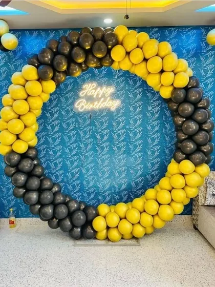 A striking yellow and black circular balloon arch. This high-contrast design with a neon sign is perfect for creating a bold and energetic party atmosphere.