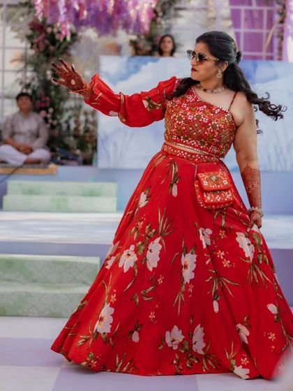 The bride showing off her dance moves. The flowing red floral lehenga was the perfect choice for this fun, high-energy welcome party, allowing her to move freely and look amazing.