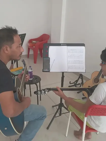A student getting help with tuning his guitar from the instructor.