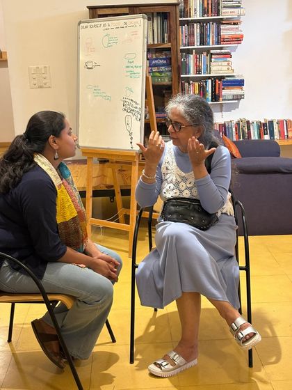 Two women engaged in an animated discussion, with a whiteboard in the background. Our gatherings often spark lively exchanges of ideas.