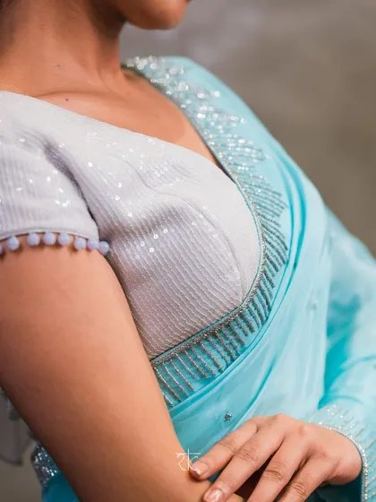 The saree is paired with a stunning all-sequin blouse, with delicate pom-pom detailing on the sleeves for a playful touch.