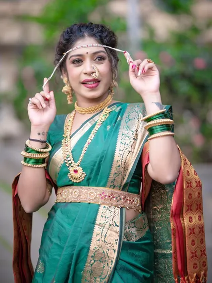 The model playfully holds her 'mundavalya', adding a touch of personality to the traditional look.