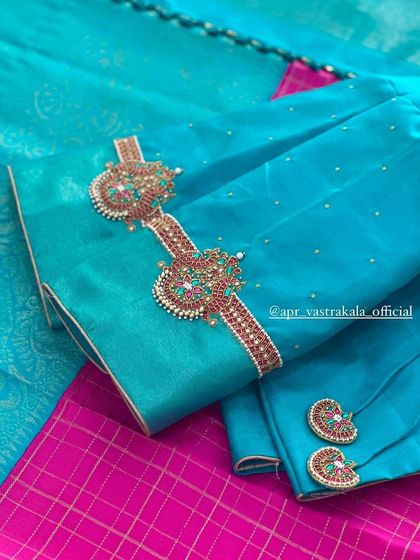 A vibrant turquoise blouse with armlet-style embroidery on the sleeves.