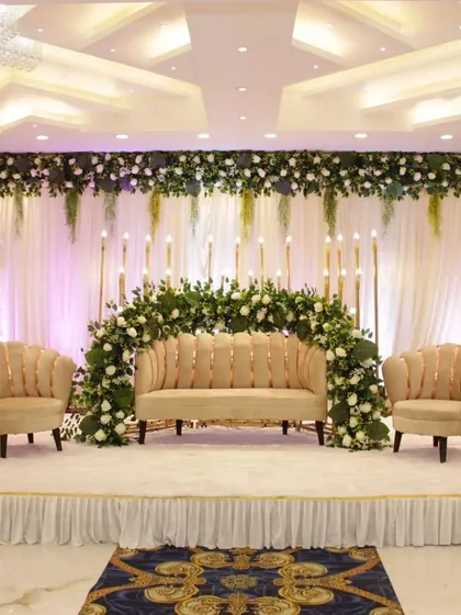 A clean and modern stage with a half-arch of white flowers and tall candle stands. This setup at Grand Utsav banquet is ideal for a sophisticated reception or Walima.