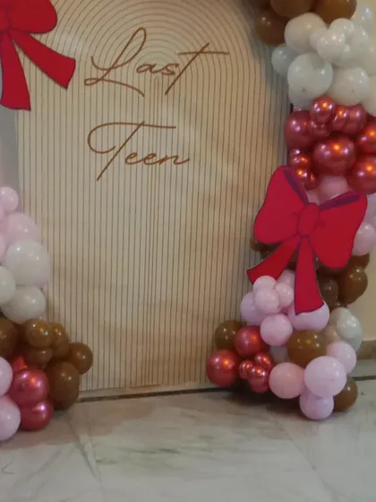 A fun and stylish "Last Teen" theme for a 19th birthday. The custom backdrop is framed by balloons in brown, pink, and white, with cute red bow accents.
