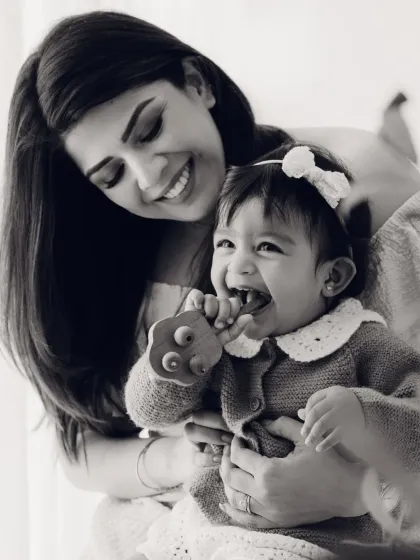 A mother holds her teething baby in this candid black and white photo. It's a real, beautiful moment of motherhood.