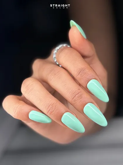 A close-up of the glossy mint green manicure. The color is soft yet eye-catching, and the stiletto shape adds a touch of drama.