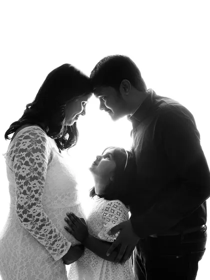 Sometimes, a simple silhouette tells the most powerful story. This artistic black and white maternity photo captures the intimate bond of a growing family, using light and shadow to create a timeless and emotional portrait.