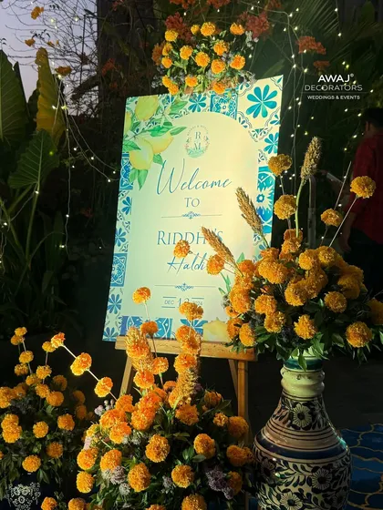 A close-up of the welcome sign at night, with fairy lights adding a magical sparkle to the marigold arrangements.