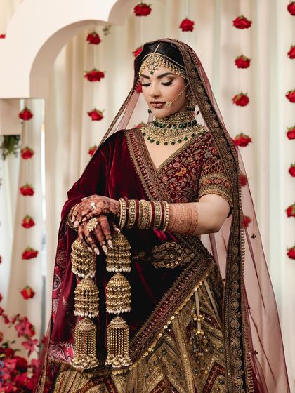 A vision in red. This bride stuns in a traditional red and gold lehenga, complete with heavy kalire, embodying the grace and beauty of a classic Indian bride.