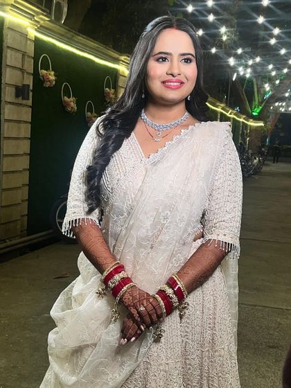Grace, glamour, and a touch of sparkle for this bride's reception. She looks stunning in an all-white lehenga with a pop of color from her traditional bangles.