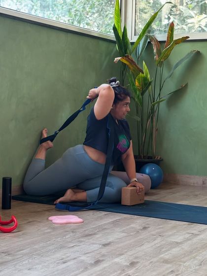 A student uses a strap to assist in a deep quad stretch, showing how props can make challenging poses more accessible.