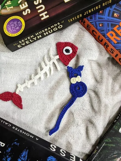 A duo of our quirky, handmade crochet bookmarks. This set features a playful cat and a fish skeleton, a perfect gift for any avid reader with a sense of humor.