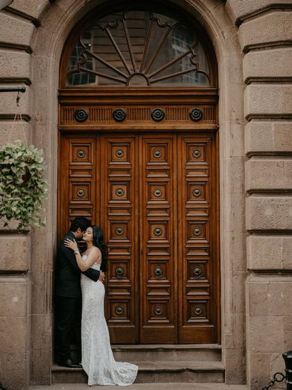 A romantic embrace in front of a magnificent wooden door, capturing a private moment against a grand, public backdrop.