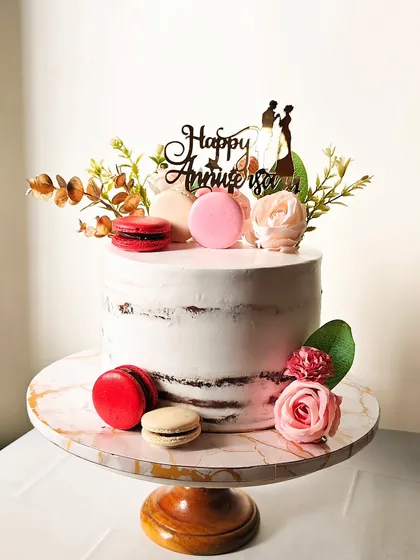 I love the rustic charm of a semi-naked cake. This anniversary cake is decorated with fresh flowers and colorful macarons, allowing the texture of the cake to peek through for a simple yet sophisticated look.