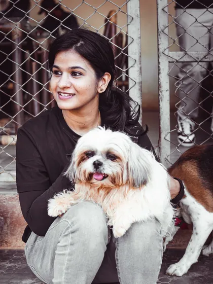 A happy visitor holds a sweet Shih Tzu on her lap, showing how easy it is to get cuddles here.