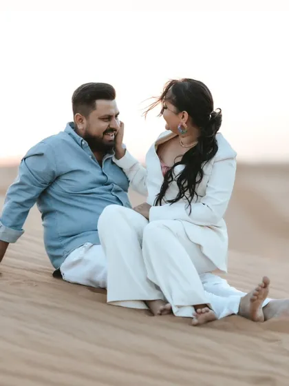 A sweet, candid moment of laughter and affection shared on the desert sand. This close-up captures the warmth and intimacy of their relationship.