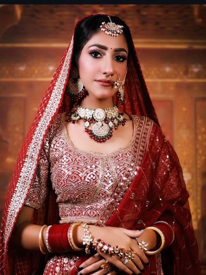 A bride in a traditional red lehenga with silver embroidery. The matching jewellery completes this classic look.