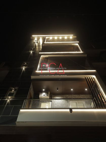 A close-up night view of the upper floors of 'The Cursive Abode'. The image details the texture of the balcony walls and the wooden ceiling, all enhanced by ambient lighting.