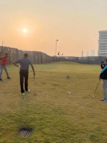 Players practicing their chipping and putting on our short game area, with the morning sun creating a perfect practice environment.