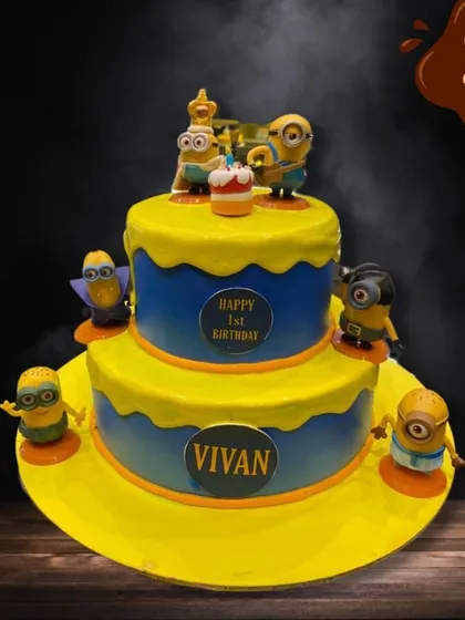 This two-tier Minions cake is full of playful mischief. The bright yellow and blue design is covered in fondant Minion characters, each with their own unique expression, perfect for a first birthday.