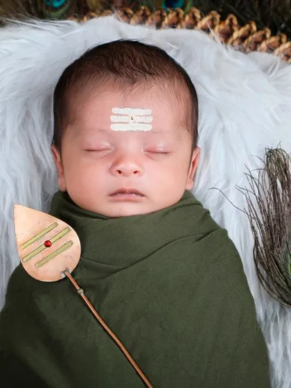 A divine little Lord Murugan. This newborn is styled with a vel and peacock feathers, a unique and spiritual theme we offer for families wanting to capture their faith.