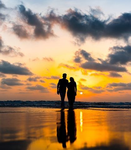 A romantic walk on the beach at sunset. The reflection of the golden sky on the wet sand adds a magical quality to this beautiful pre-wedding silhouette.