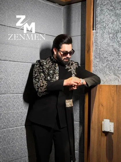 The model checking his watch while wearing the black and gold asymmetrical Indo-Western. A stylish and confident look.