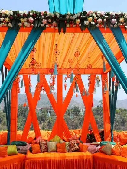 A vibrant Mehendi seating area with a stunning mountain view. The orange and teal decor creates a beautiful contrast with the natural surroundings.