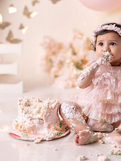 This little angel is having a blast with her cake. A first birthday cake smash is a memory to cherish forever.