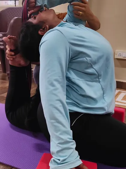 A close-up of the hands-on adjustment for Full Pigeon Pose. This ensures the student is opening their shoulders and back correctly without putting strain on their joints.