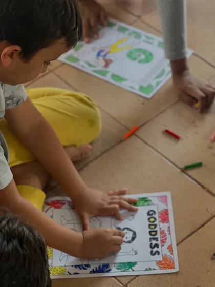 A young boy focuses on coloring a Goddess Pose worksheet. These quiet activities are a form of meditation, helping to calm their minds.