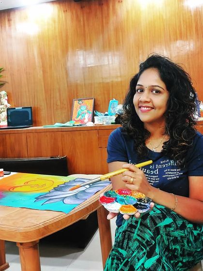 Me at my table, smiling with my palette. Painting is where I find my happiness and authenticity.