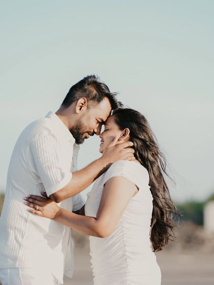 A tender moment captured in the golden hour light. The soft focus and warm tones enhance the romance of this beach pre-wedding portrait.