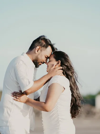 A tender moment captured in the golden hour light. The soft focus and warm tones enhance the romance of this beach pre-wedding portrait.