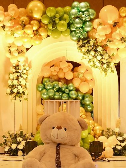 A giant teddy bear sits proudly in front of a stunning balloon arch backdrop. This creates a fantastic photo opportunity and a grand statement piece for the event.