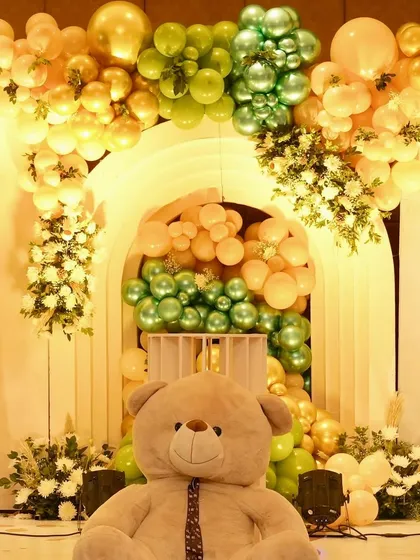 A giant teddy bear sits proudly in front of a stunning balloon arch backdrop. This creates a fantastic photo opportunity and a grand statement piece for the event.