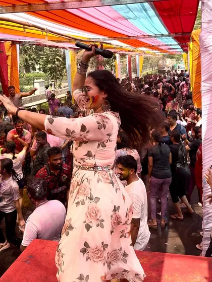 A dynamic action shot of me dancing and engaging with the massive crowd at the Holi celebration.