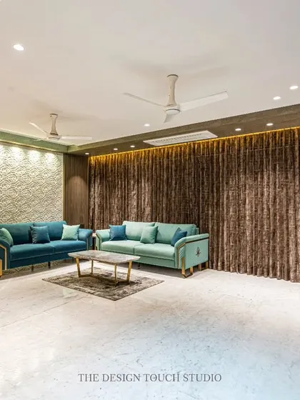 A wide shot capturing the full living area, with its plush teal sofas and rich, dark curtains. The design emphasizes comfort and style, creating a perfect setting for both relaxation and entertaining.