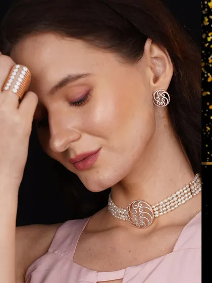 A model wears a unique pearl choker with a central rose gold and diamond motif, paired with matching earrings and ring.