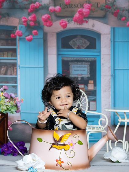 A sweet moment in a Parisian cafe, with this little girl sitting in a watering can surrounded by flowers.