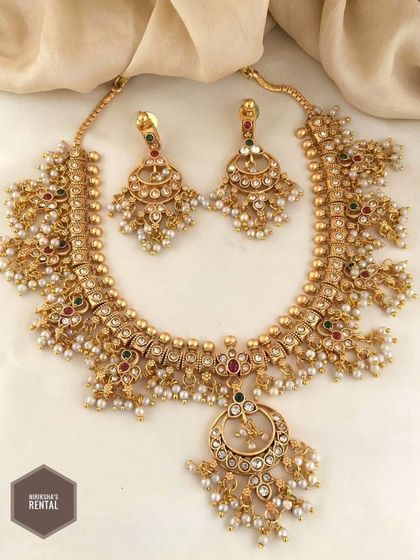A stunning choker necklace set with pearl clusters and a crescent-shaped pendant, perfect for a reception or sangeet look.