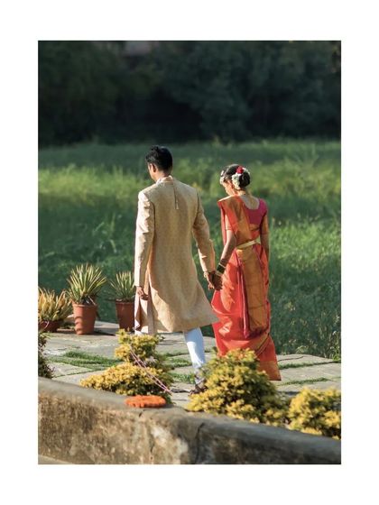 The couple walks away hand in hand through a lush green path. A quiet, candid moment that feels both peaceful and romantic.