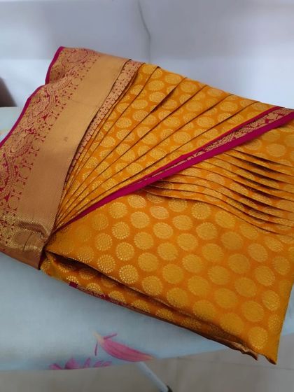 This image showcases the final result of my pre-pleating and box folding service on a beautiful yellow saree.