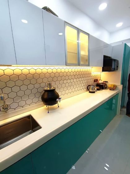 This perspective highlights the long, uninterrupted white countertop, providing ample workspace. The glass-fronted upper cabinets add a sense of lightness to the design.