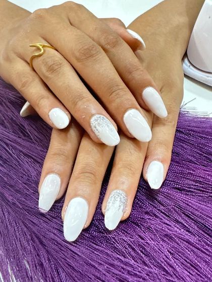 A clean and bright birthday nail set. The glossy white nails are paired with a silver glitter accent nail for a touch of celebration.